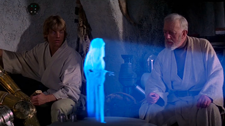 Luke Skywalker (Mark Hamill) and Obi-Wan Kenobi (Alec Guinness) watch a message from Princess Leia (Carrie Fisher) in Star Wars: Episode IV — A New Hoope